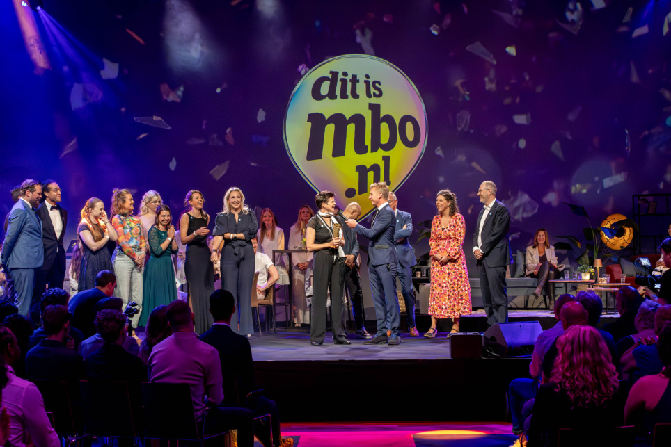Het onderwijsteam van Roc Nijmegen staat samen op een podium met de onderwijsminister Eppo Bruins tijdens de uitreiking van de 'Onderwijsteam van het Jaar 2025'-prijs - foto hoort bij het nieuwsbericht op AOb.nl over het onderwijsteam van het jaar in het mbo.